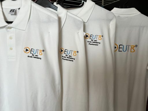 Weiße Poloshirts mit dem Logo von EUR16 auf der Brust.
